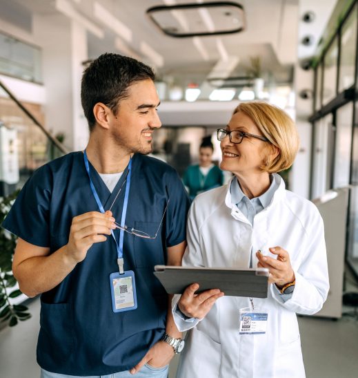 Senior female doctor talking to her young colleague in office corridor