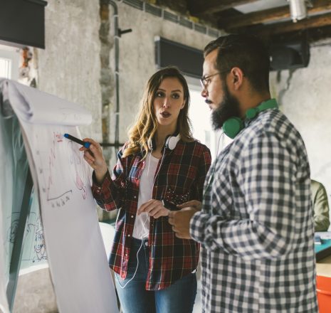 Coworkers on meeting in the office. Standing in front of flipchart and discussing